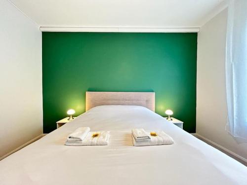 une chambre avec un lit blanc avec un mur vert dans l'établissement Forum Flower spacieux T2 au coeur de la ville, à Reims