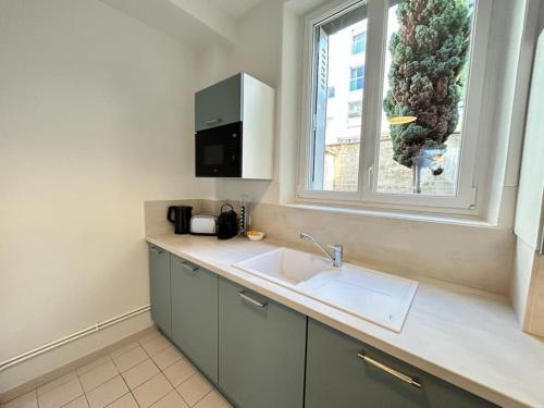 une cuisine avec un évier et une fenêtre dans l'établissement Forum Flower spacieux T2 au coeur de la ville, à Reims