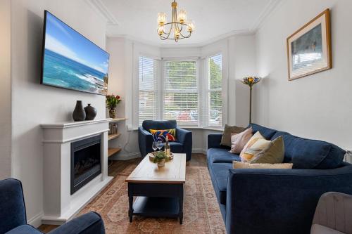 a living room with a blue couch and a tv at Maple House - Park View Sleeps 7 in Exeter