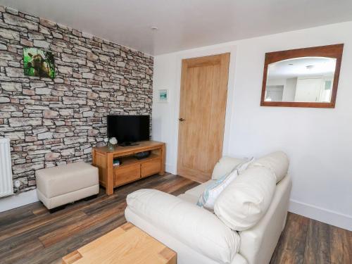 a living room with a white couch and a stone wall at Field View in Llanybydder