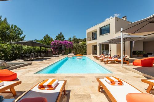 a villa with a swimming pool and lounge chairs at La Villa Monarque in Cap d'Agde