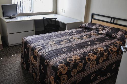 a bedroom with a bed and a desk with a computer at Residence & Conference Centre - Kitchener-Waterloo in Kitchener