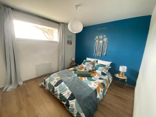 a bedroom with a bed and a blue wall at Un cocon face à la plage in Saint-Trojan-les-Bains