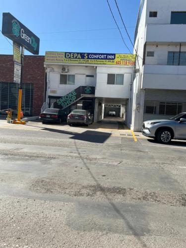 a parking lot with cars parked in front of a building at Depas Conford inn in Cuauhtémoc