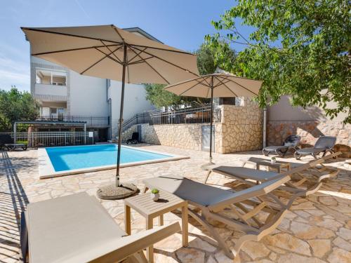 un patio con sillas y sombrillas junto a una piscina en Apartment Relax-3 by Interhome, en Jasenice
