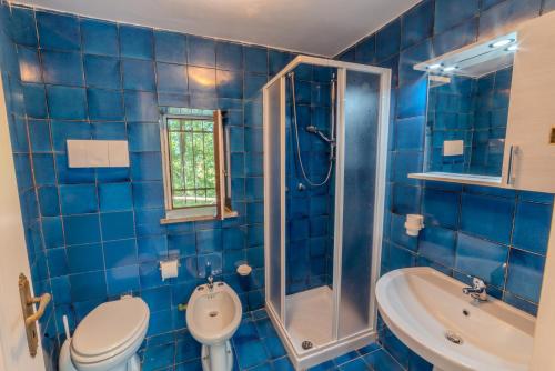 a blue tiled bathroom with a toilet and a sink at Il Borgo nel bosco in Canterano