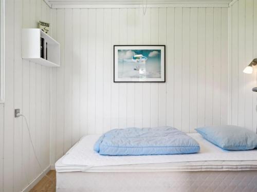 a bed in a white room with a picture on the wall at Holiday Home Aleta - 600m from the sea by Interhome in Grenå