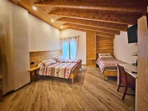 a bedroom with two beds and a desk and a table at La Genzianella affittacamere in Santo Stefano dʼAveto