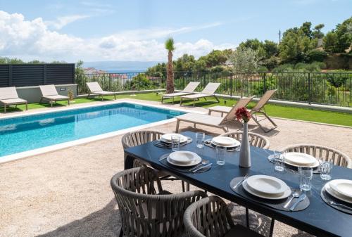 a dining table and chairs next to a swimming pool at Luxury Villa David 1 - heated pool 38m2 in Podstrana