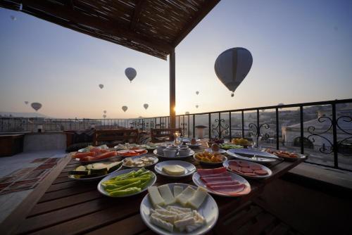 Una mesa de comida en un balcón con globos aerostáticos. en Pashahan Hotel, en Göreme