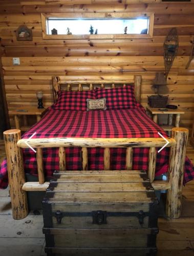 a bed in a log cabin with a wooden wall at Gables Cedar Creek Inn in Twain Harte