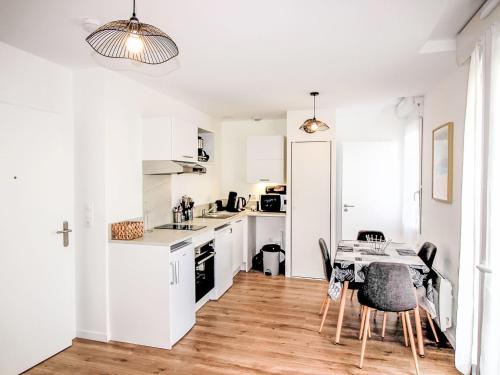 une cuisine avec des armoires blanches et une table et des chaises dans l'établissement Apartment Cap Océan-7 by Interhome, à Capbreton
