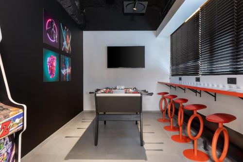 a room with red chairs and a table and a tv at Aloft Hotel, By Marriott in Dijon
