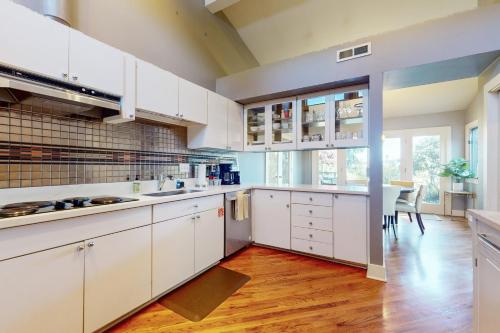 a kitchen with white cabinets and a wooden floor at Stones Way in Lake Forest Park