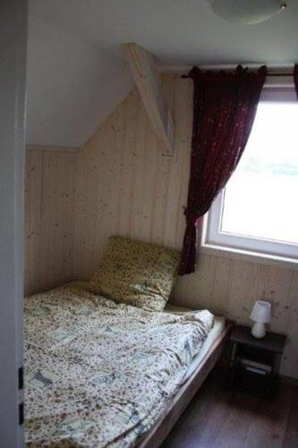 a bed in a room with a window at Domek piętrowy klimatyzowany, ogrzewany z jacuzzi na terenie ośrodka- Domki u Staszka in Rusinowo