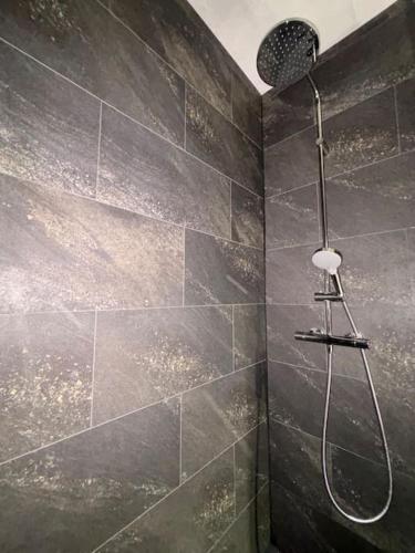 La salle de bains est pourvue d'une douche et de carrelage noir. dans l'établissement Le Nocturno, à Cluses