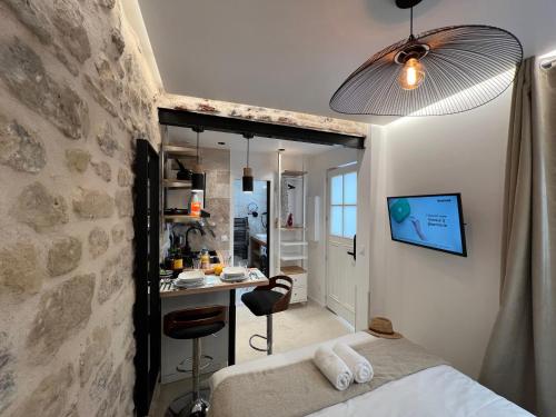 - une chambre dotée d'un mur en pierre avec un lit et un bureau dans l'établissement Studios Clouet-Paris Centre- XVe!, à Paris