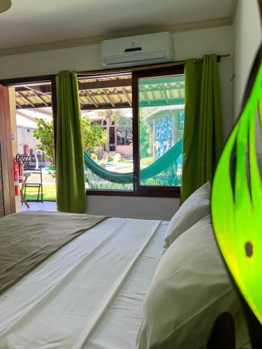 a bedroom with a bed and a window with a slide at Pousada Aconchego de Genipabu in Jenipabu