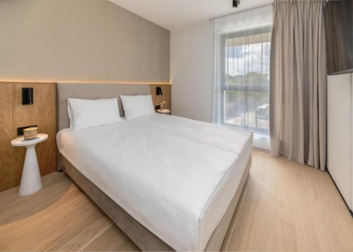 a bedroom with a large white bed and a window at Apartamenty na Półwyspie Wydma&Las in Jastarnia