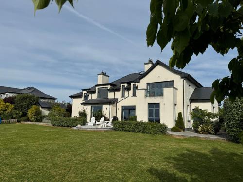 a large white house with a green lawn at Your Coastal Paradise Awaits in Oranmore
