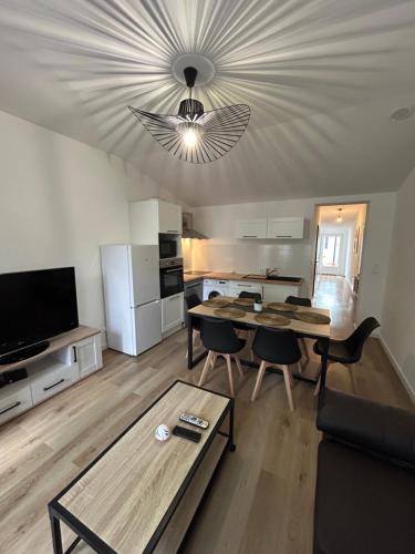 a living room with a table and a kitchen at Belle petite maison proche de la mer in Les Sables-dʼOlonne