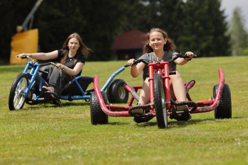 two girls riding on tricycles in a field at Penzion Rotunda in Harrachov