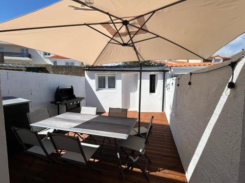 a table and chairs with an umbrella on a deck at Belle petite maison proche de la mer in Les Sables-dʼOlonne