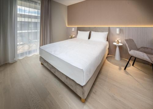 a bedroom with a large white bed and a chair at Apartamenty na Półwyspie Wydma&Las in Jastarnia