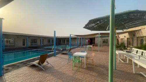 a patio with a table and chairs next to a pool at ghroob farmhouse villa in Al Ḩamrānīyah