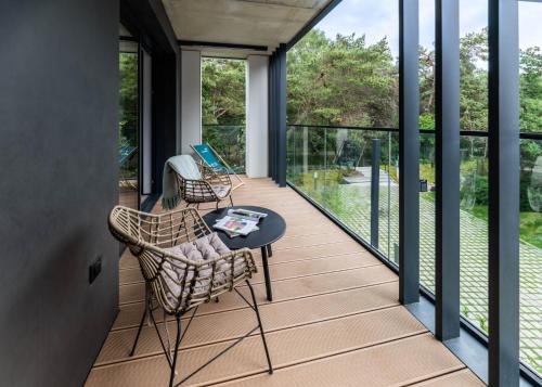 a screened in porch with a table and chairs on it at Apartamenty na Półwyspie Wydma&Las in Jastarnia