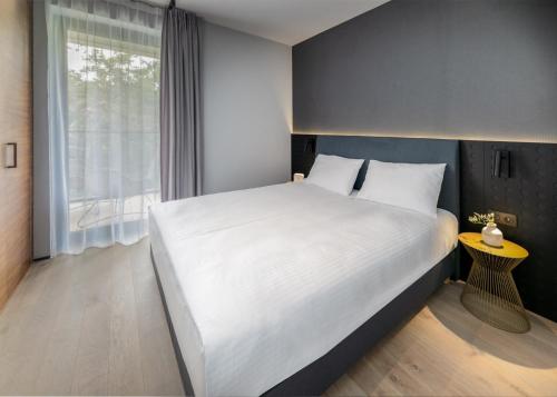 a bedroom with a large white bed and a window at Apartamenty na Półwyspie Wydma&Las in Jastarnia