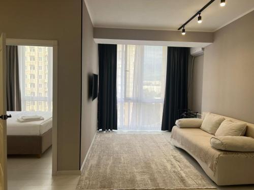 a living room with a couch and a large window at Sholpan city comfort in Almaty