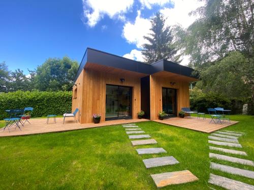a small house with a deck and grass at L'Oustal Des Dômes in Orcines
