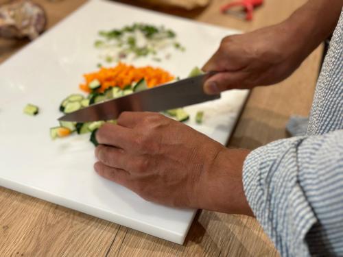a person cutting vegetables on a white cutting board at L'enthousiasme in Prades