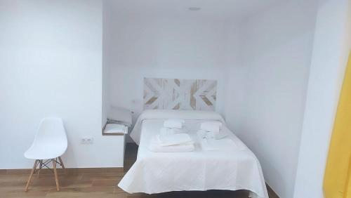 a white bedroom with a bed with towels on it at Abuela Maruja in Cazorla