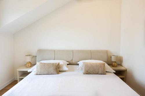 a bedroom with a large white bed with two pillows at Sea view APARTMENT PEPE in Podstrana