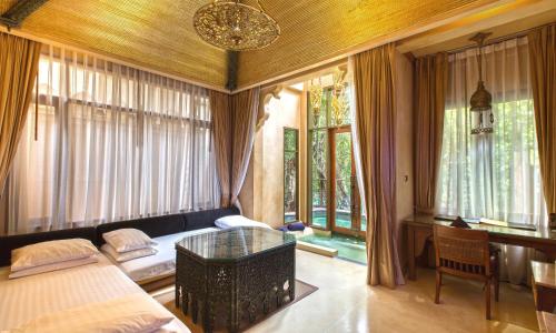 a bedroom with a bed and a table and windows at The Baray Villa by Sawasdee Village in Kata Beach