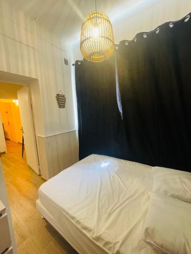 - une chambre avec un lit blanc et un lustre dans l'établissement Appartement 4 personnes à 2mn des plages, à Toulon