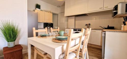 une cuisine avec une table blanche avec des chaises et une table dans l'établissement Charmant appartement, à Banyuls-sur-Mer