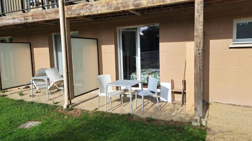 une terrasse avec une table et des chaises dans une maison dans l'établissement Joli studio piscine et parking 3km Honfleur, à Équemauville