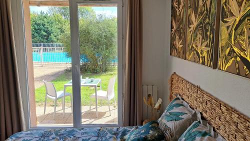 une chambre avec un lit, une table et des chaises dans l'établissement Joli studio piscine et parking 3km Honfleur, à Équemauville