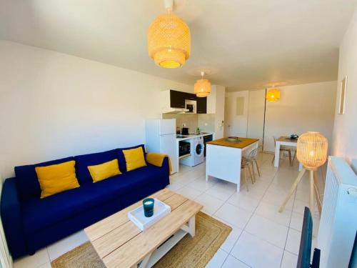 un salon avec un canapé bleu et une cuisine dans l'établissement ''Loulou'' T1 moderne et lumineux, centre ville, wifi, parking, à Sète
