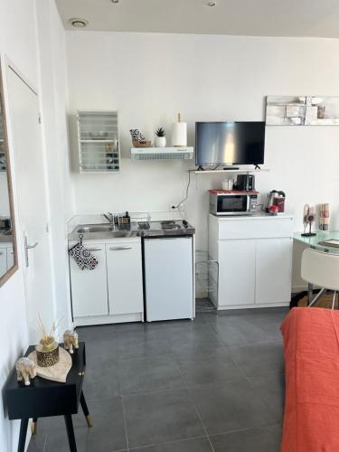 une petite cuisine avec des armoires blanches et un micro-ondes dans l'établissement Cosy Cannes Studio, à Cannes