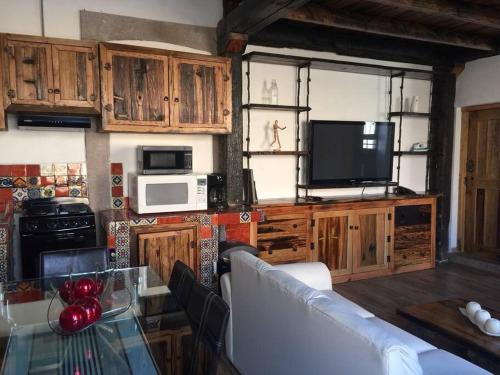 a kitchen with wooden cabinets and a table with a television at Mexican Loft by LA Casa Cosme in the city center in San Luis Potosí