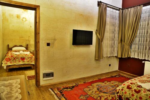 a bedroom with a bed and a television on a wall at Ürgüp Inn Cave Hotel in Urgup