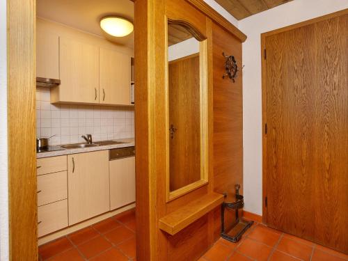a kitchen with white cabinets and a wooden door at Apparthof Sunnwies in Oetz