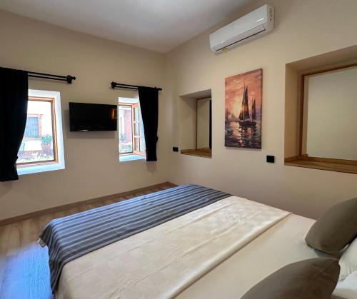 a bedroom with a bed and a tv and windows at Bodrum Konağı in Bodrum City