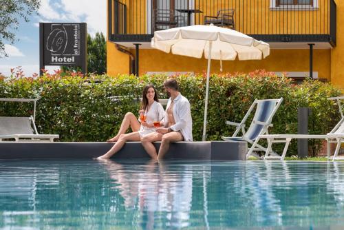 a man and woman sitting on the edge of a swimming pool at Residence Al Frantoio in Arco