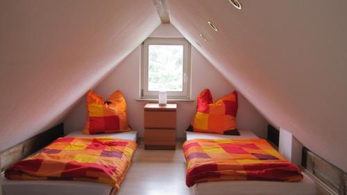 ドレスデンにあるFerienwohnung im Grünen von Dresdenのベッド2台と窓が備わる屋根裏部屋です。