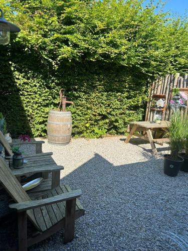 a garden with two benches and a barrel and a chair at La Fattoria Bed&breakfast in Venhuizen